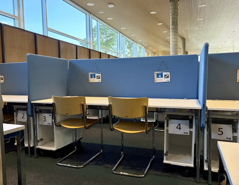 Ein Tisch mit zwei Stühlen, Trennwänden und Containern